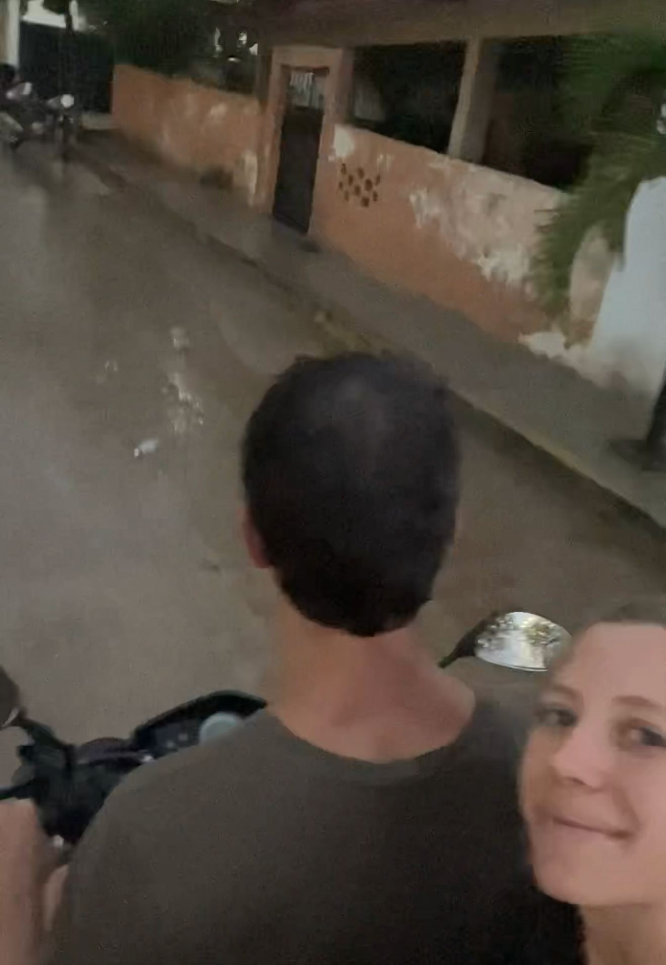 A blurry roadside selfie on a scooter in a foreign city at dusk