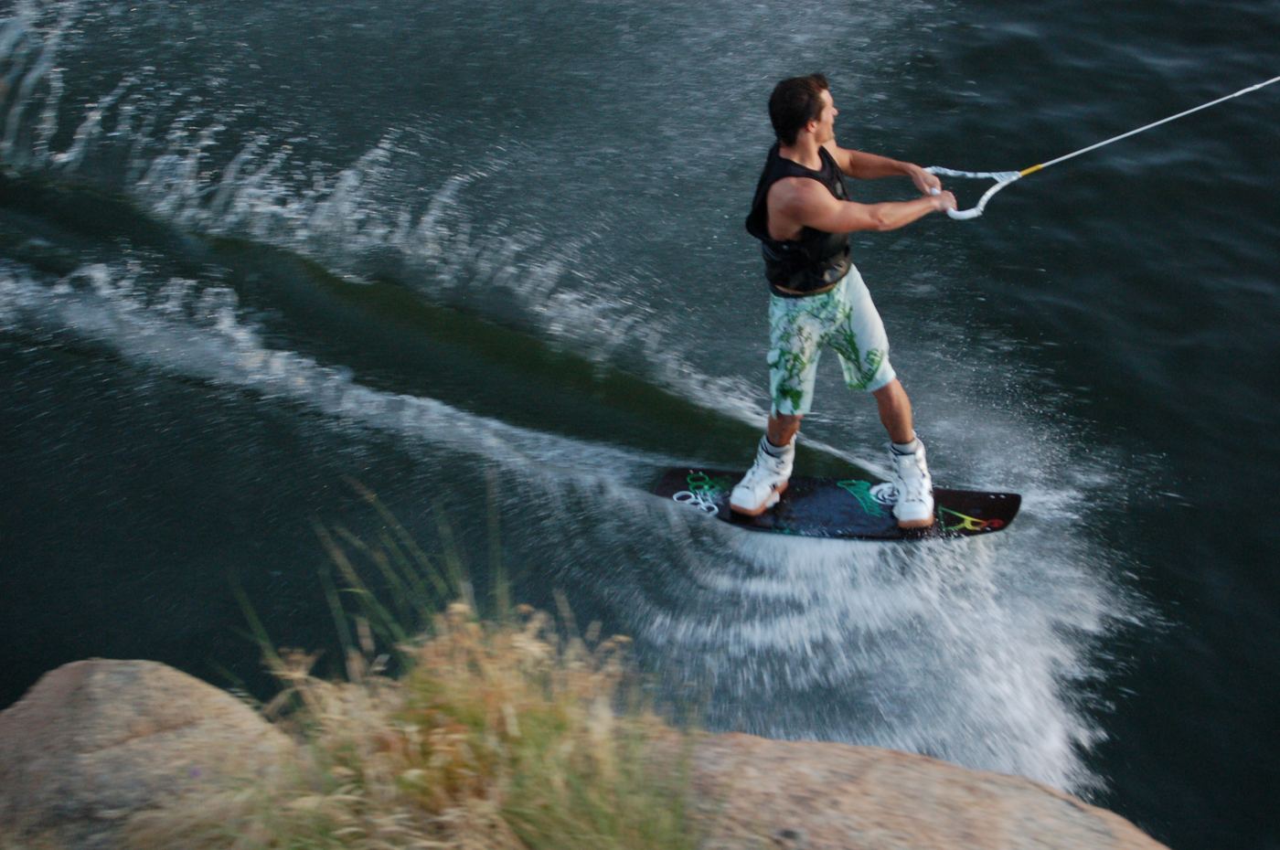 Wakeboarding behind a boat, cutting a spray of water