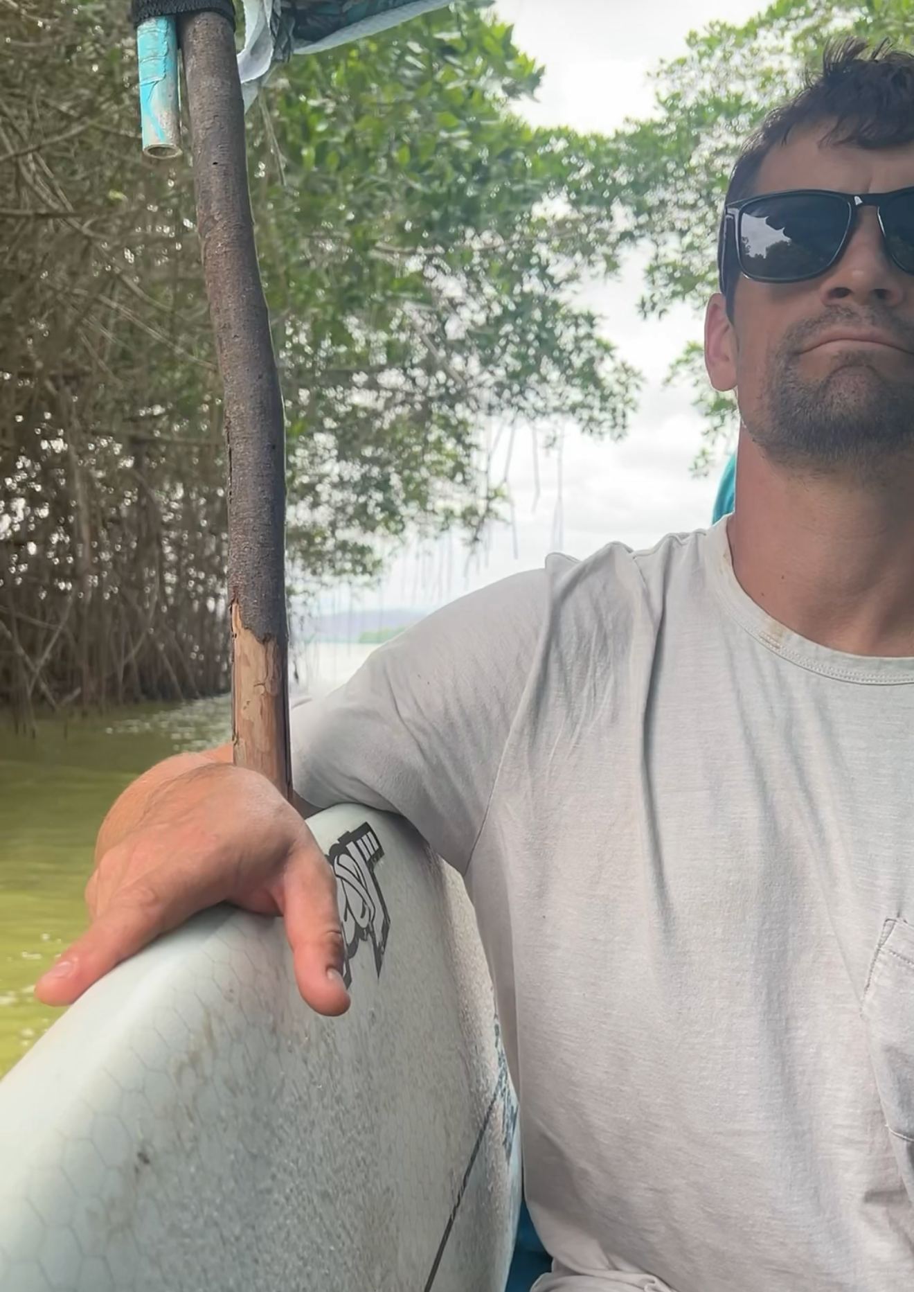 Paddleboarding through a mangrove channel, holding the paddle against the board