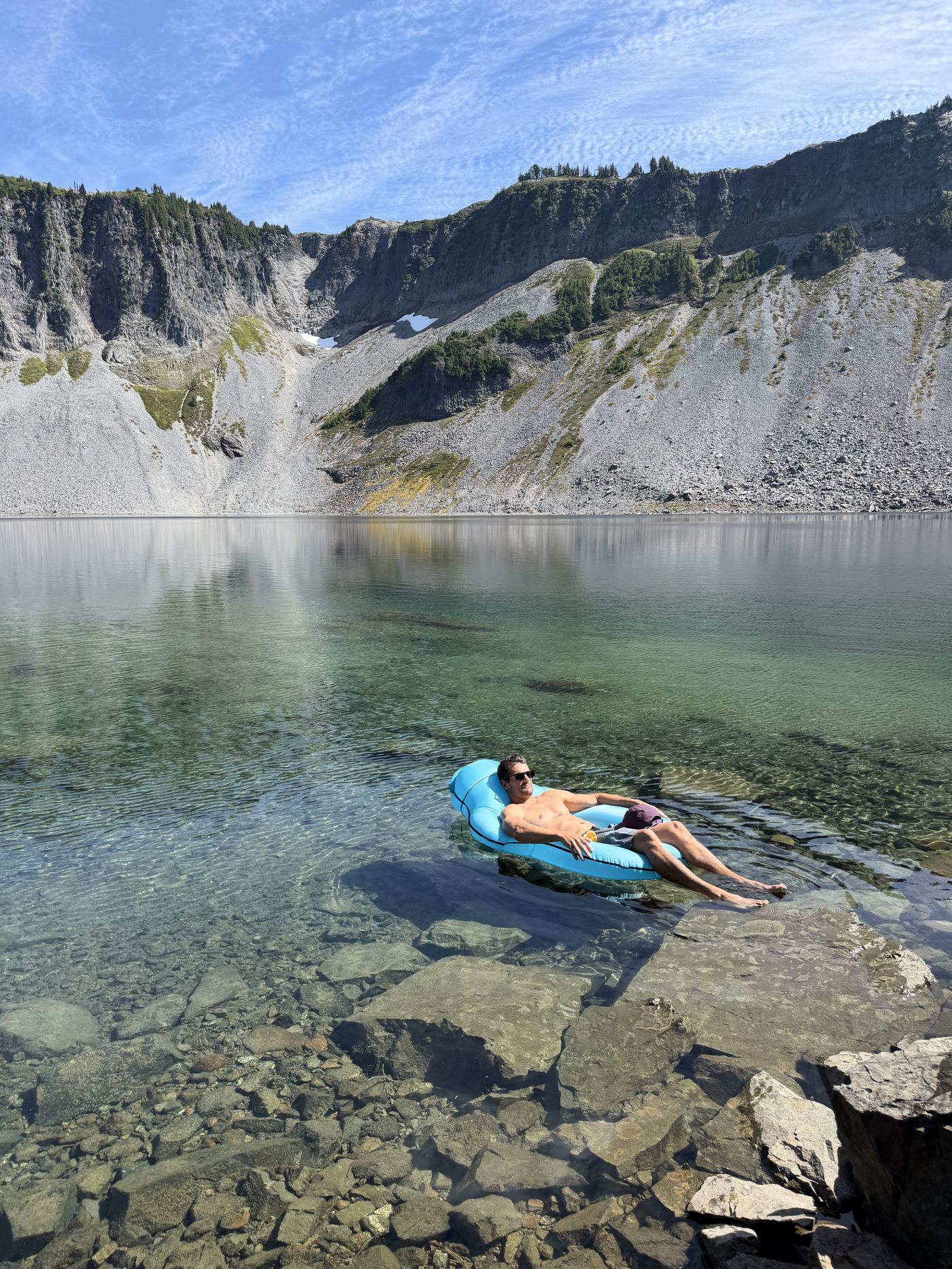 Floating on an inflatable raft in a clear alpine lake surrounded by cliffs
