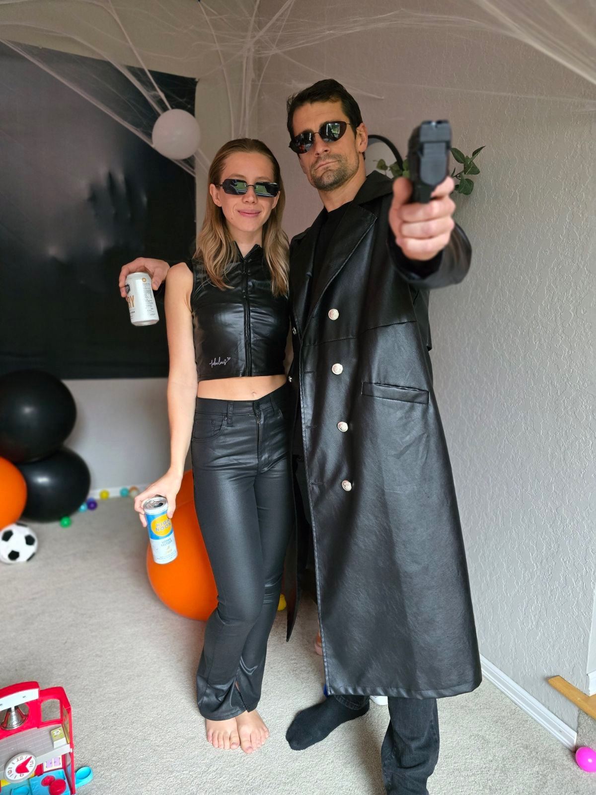 Two people in matching black leather Halloween costumes at a party
