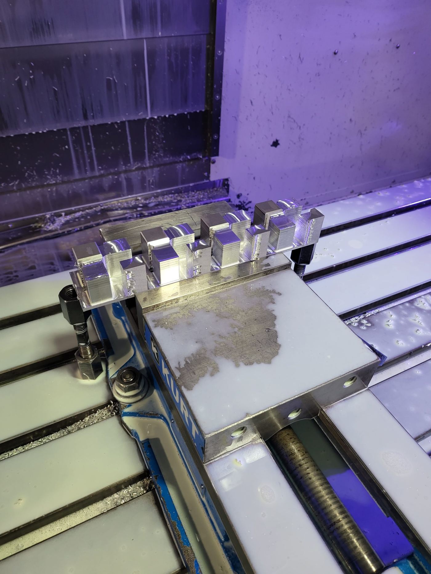 Small aluminum blocks staged in a Kurt vise for CNC machining