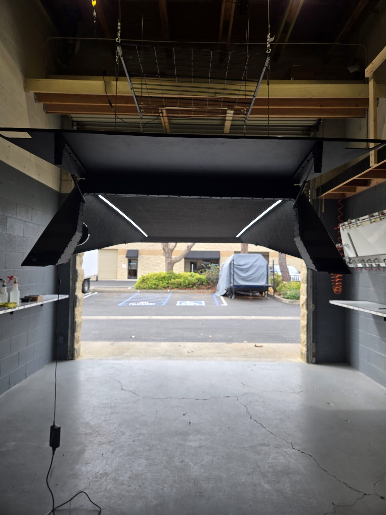 Looking out of the shop through a cap with both hatches raised, LED light strips lit along the inside edges