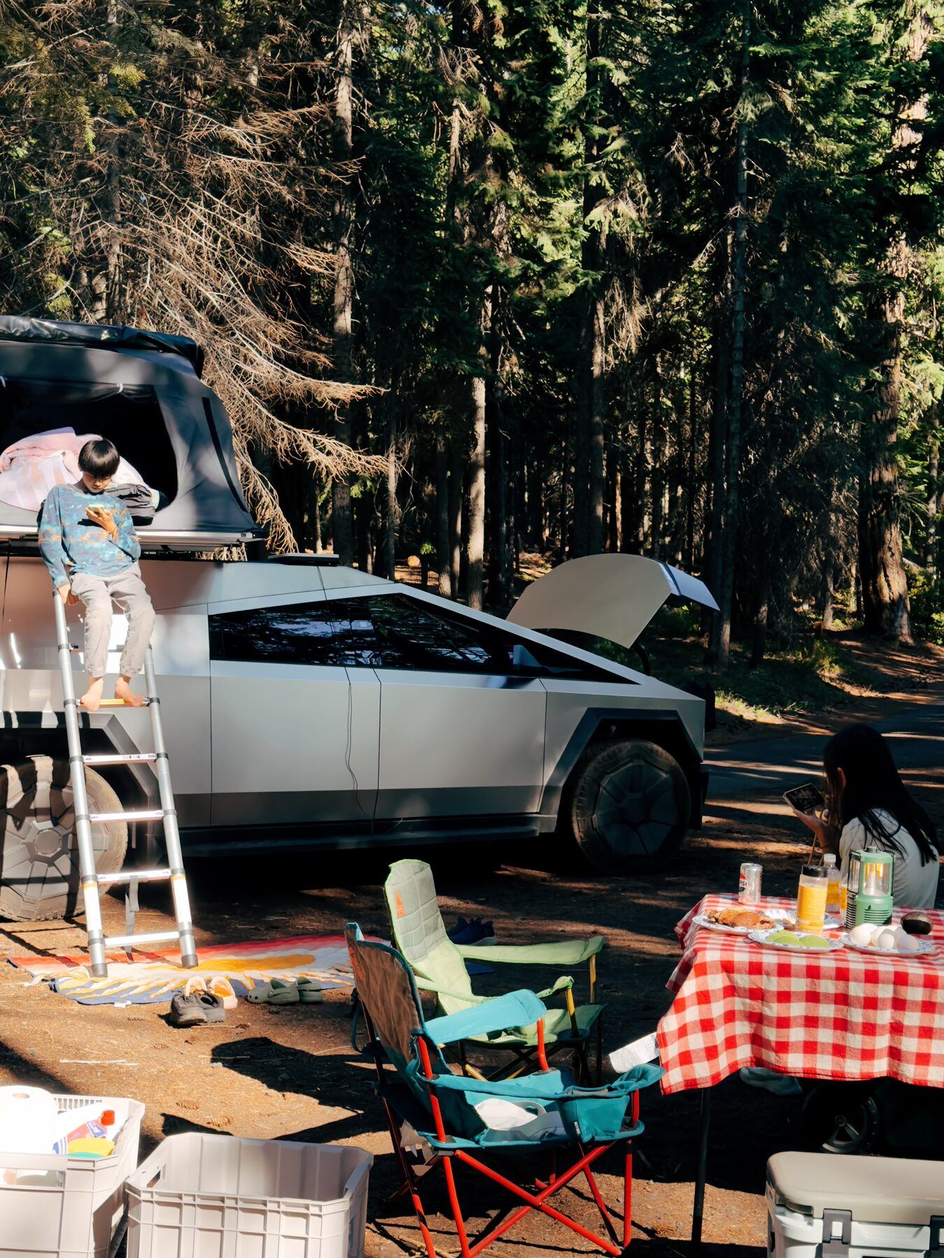 A family camp setup around the truck, one kid on the tent ladder and the cap side hatch propped open