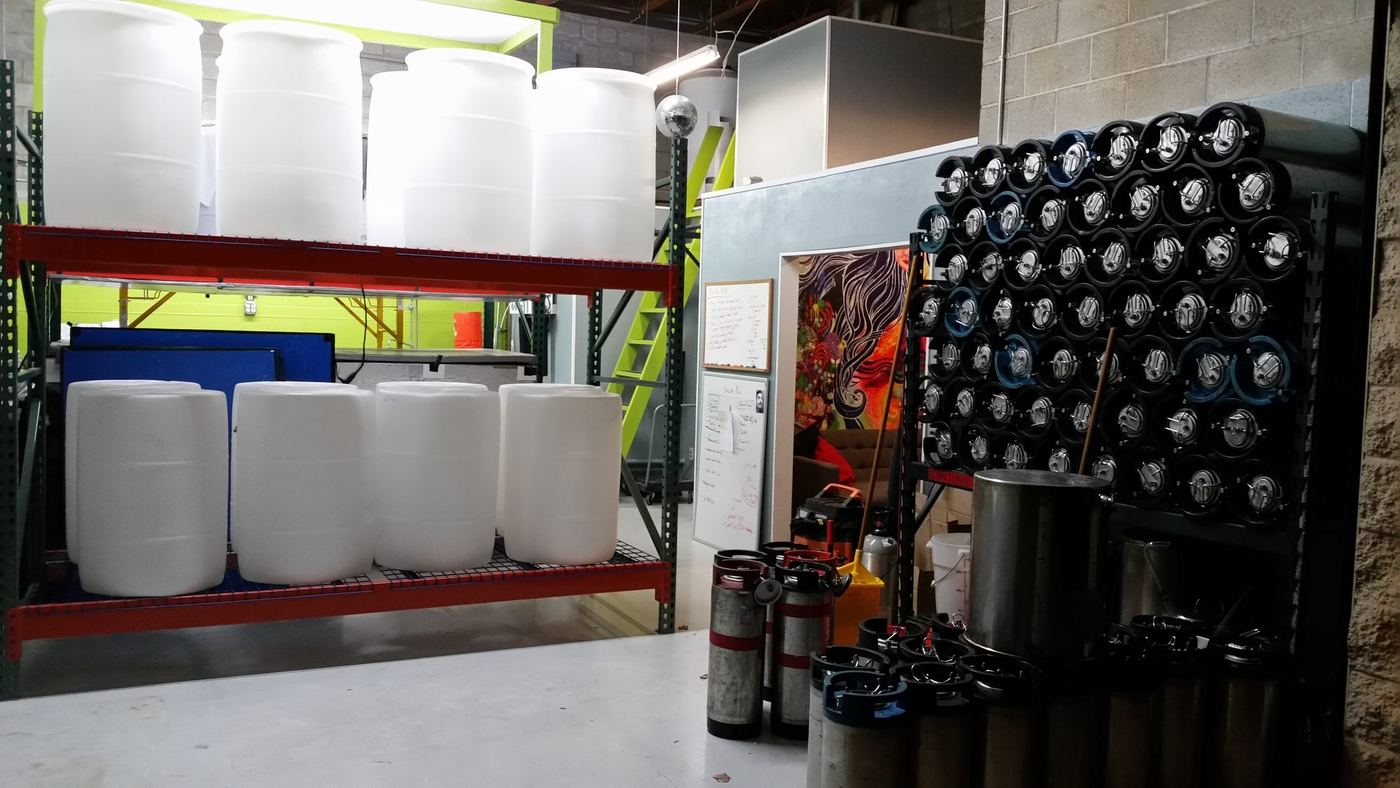 The first building, with poly fermentation barrels racked two levels high and a wall of kegs alongside them