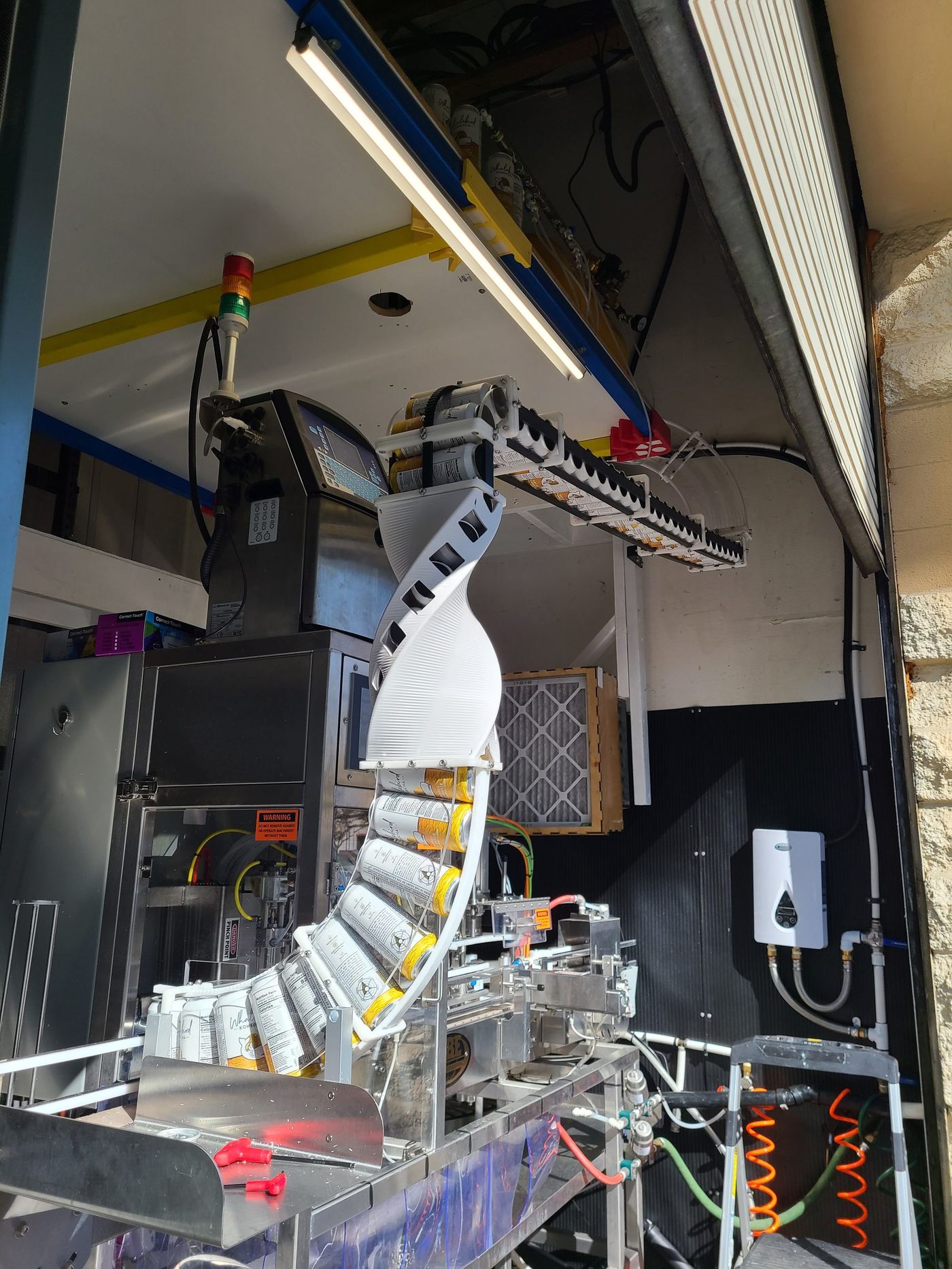 The 3D printed arm guiding cans into the line