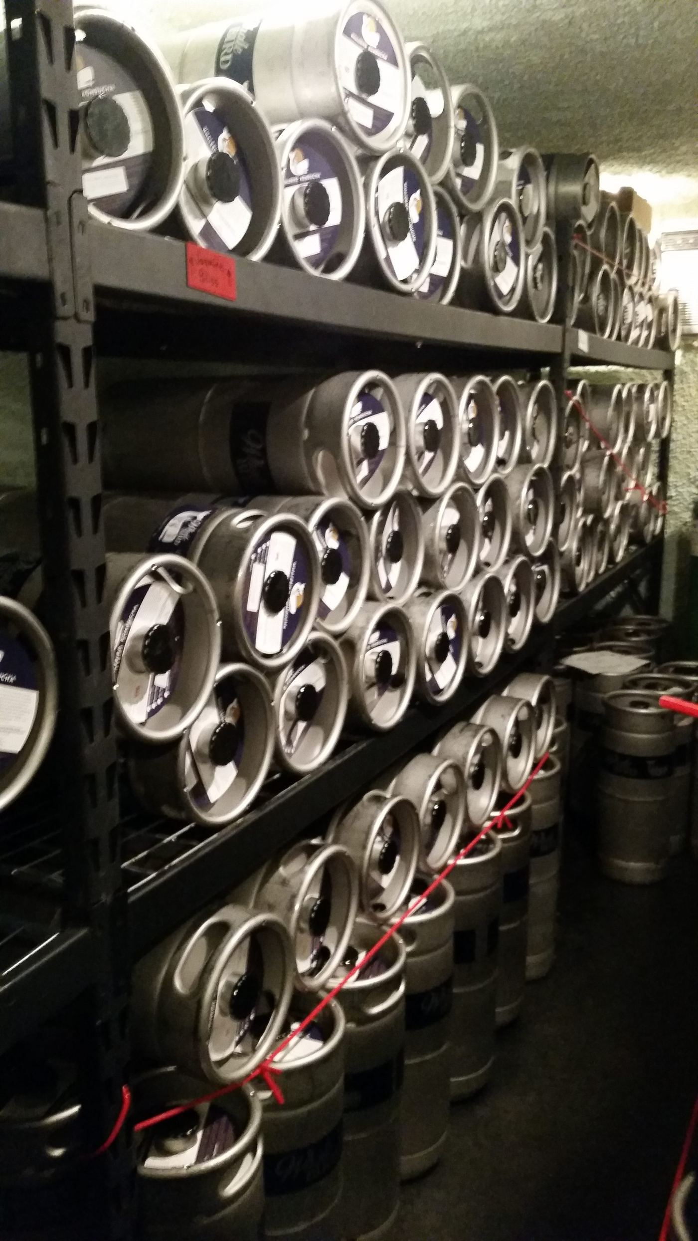 Shelving racks packed with kegs inside the finished, well-lit cold room