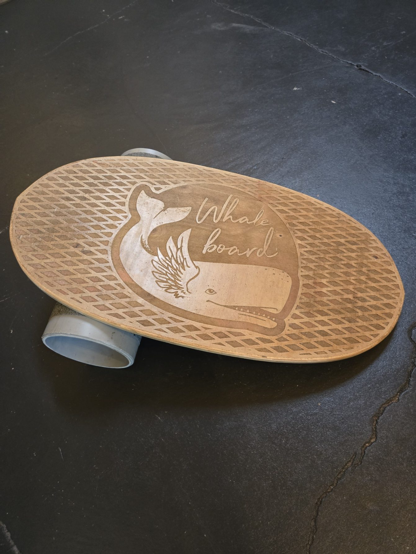 A laser-engraved wood balance board punning on 'Whale board,' etched with the Whale Bird logo