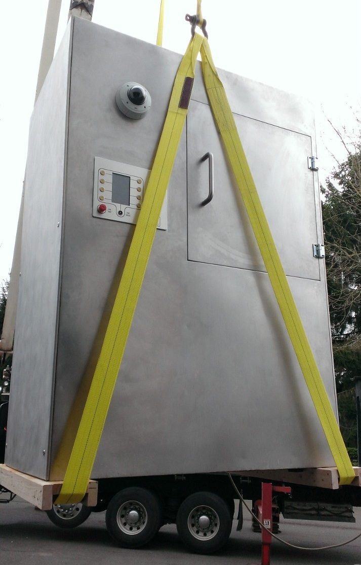 The stainless control enclosure strapped and loaded on a flatbed truck, ready for transport