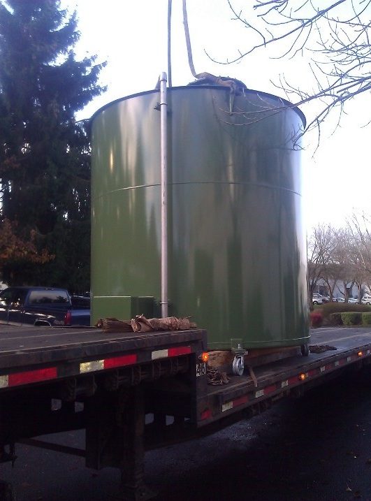 The green digester tank sitting loaded on the flatbed trailer bed, ready for the drive