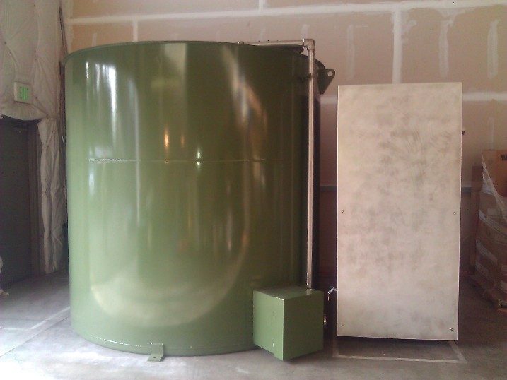 The finished green tank and stainless enclosure, straight-on view against the shop wall